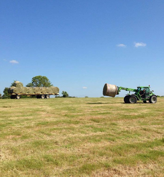 tracteur tractant une botte de foin sur une remorque