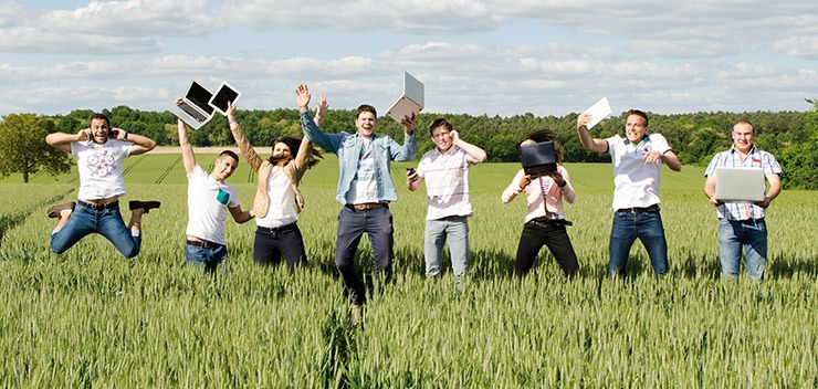 Groupe d'étudiant dans un champ d'herbes hautes avec des appareils électroniques dans les mains